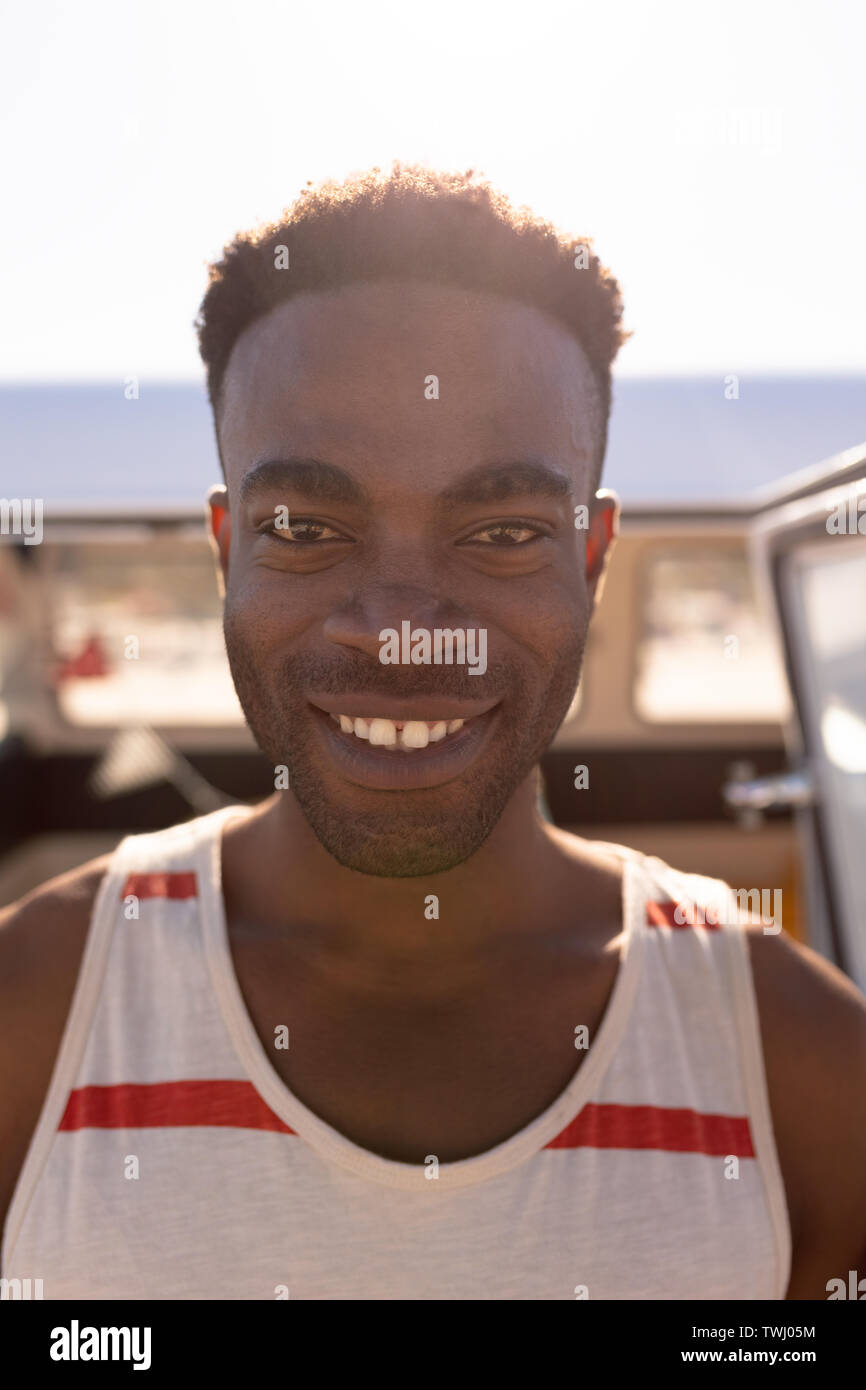 Jeune homme debout près de camping-van at beach Banque D'Images