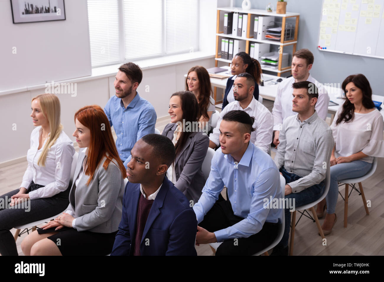 Groupe diversifié de gens d'affaires assis sur une chaise dans la salle de conférence Banque D'Images