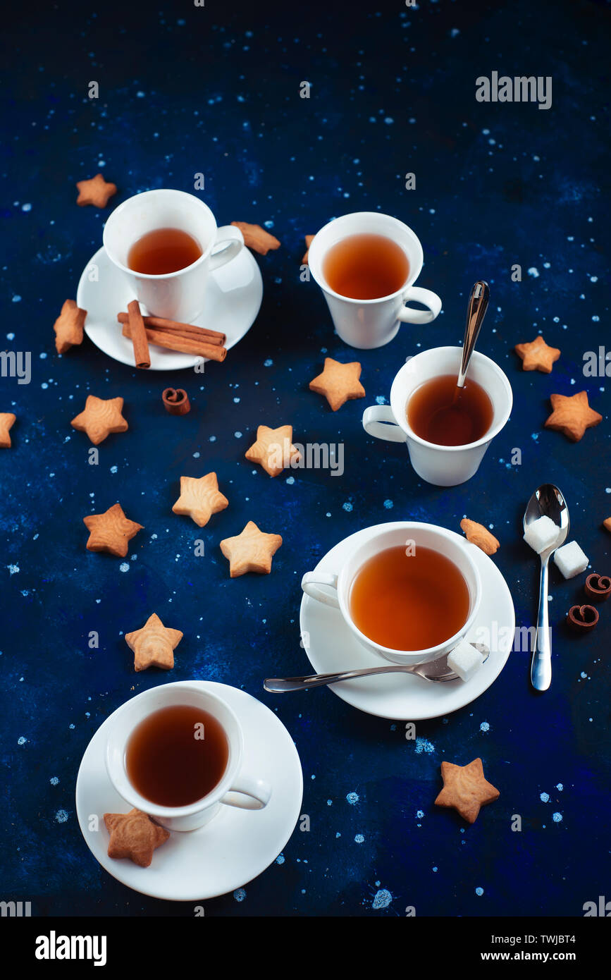 L'heure du thé avec des biscuits en forme d'étoile. Tasses en porcelaine blanche sur un fond de ciel étoilé. L'espace et l'astronomie la photographie culinaire. Banque D'Images