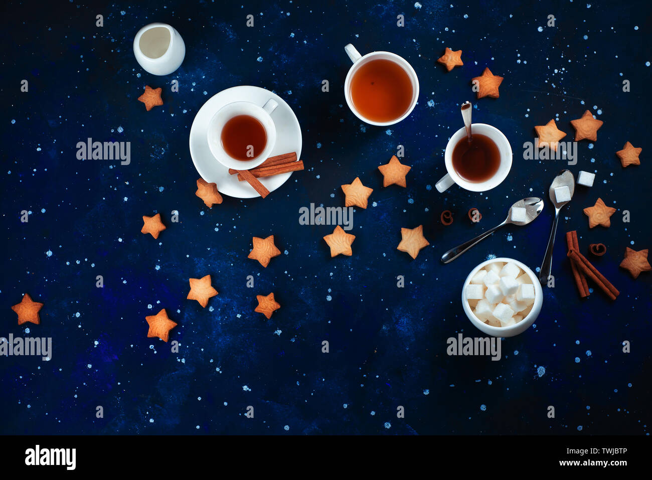 L'heure du thé avec des biscuits en forme d'étoile. Tasses en porcelaine blanche sur un fond de ciel étoilé. L'espace et l'astronomie la photographie culinaire. Banque D'Images