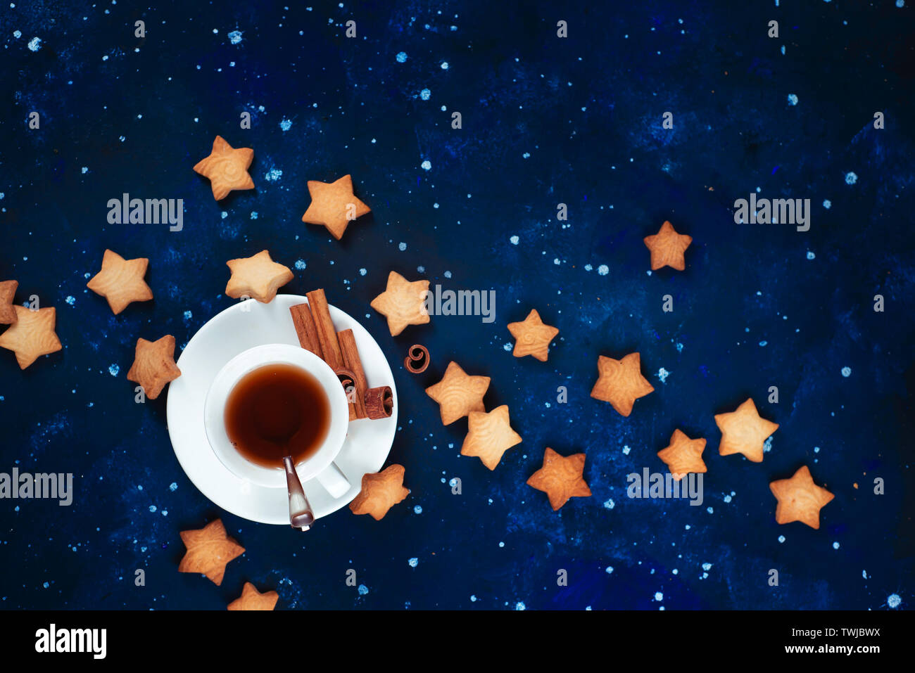 L'astronomie et de constellation avec copie espace télévision lay. L'heure du thé avec des biscuits en forme d'étoile. Tasses en porcelaine blanche sur un fond de ciel étoilé. Banque D'Images