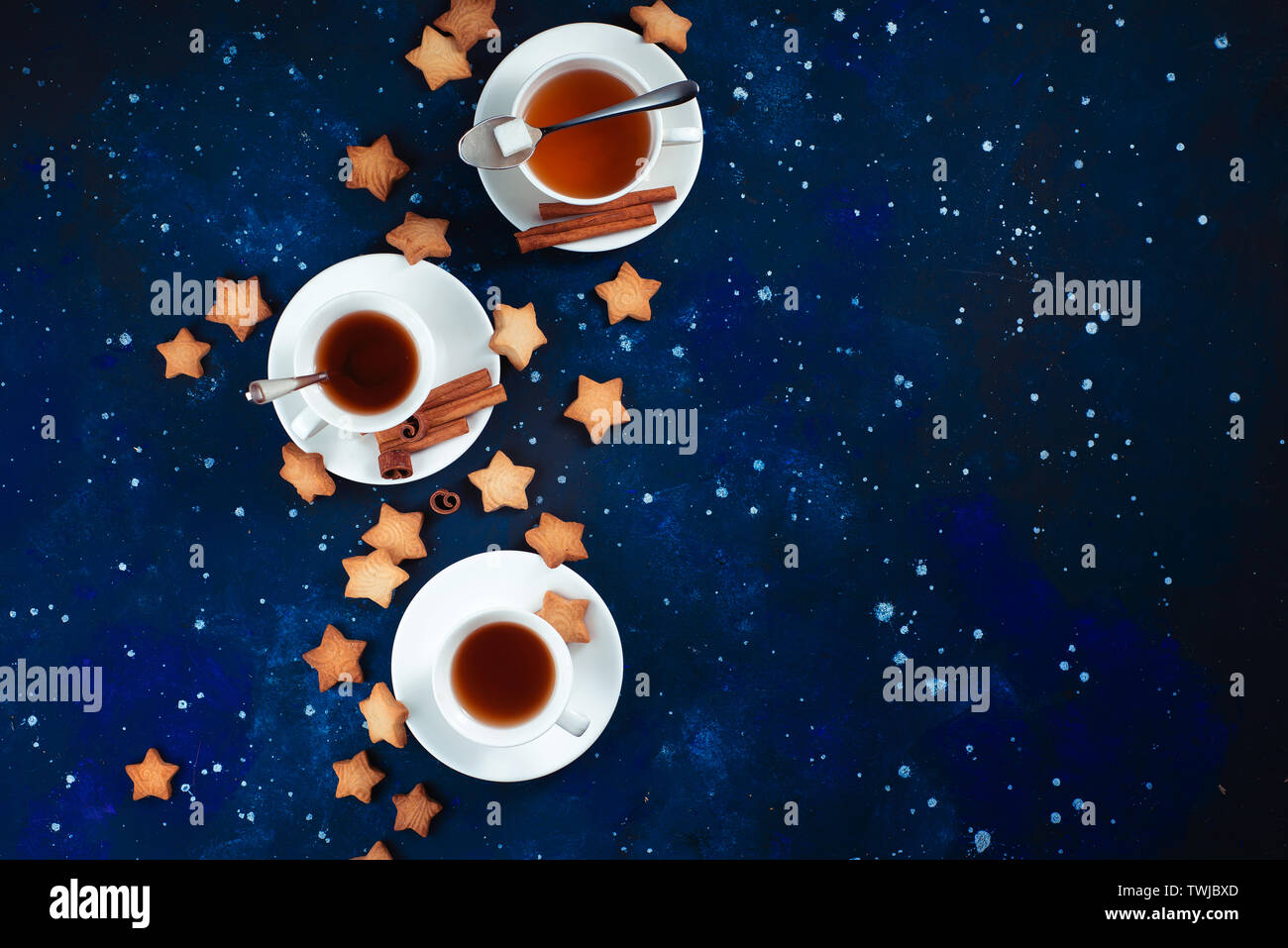L'astronomie et de constellation avec copie espace télévision lay. L'heure du thé avec des biscuits en forme d'étoile. Tasses en porcelaine blanche sur un fond de ciel étoilé. Banque D'Images