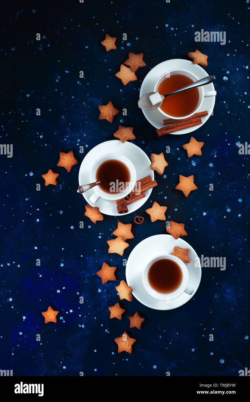 L'heure du thé avec des biscuits en forme d'étoile. Tasses en porcelaine blanche sur un fond de ciel étoilé. L'espace et l'astronomie la photographie culinaire. Banque D'Images