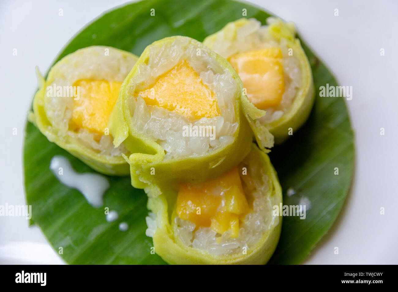 Le riz gluant à la mangue avec du lait de coco rouleau sur la feuille de banane Banque D'Images