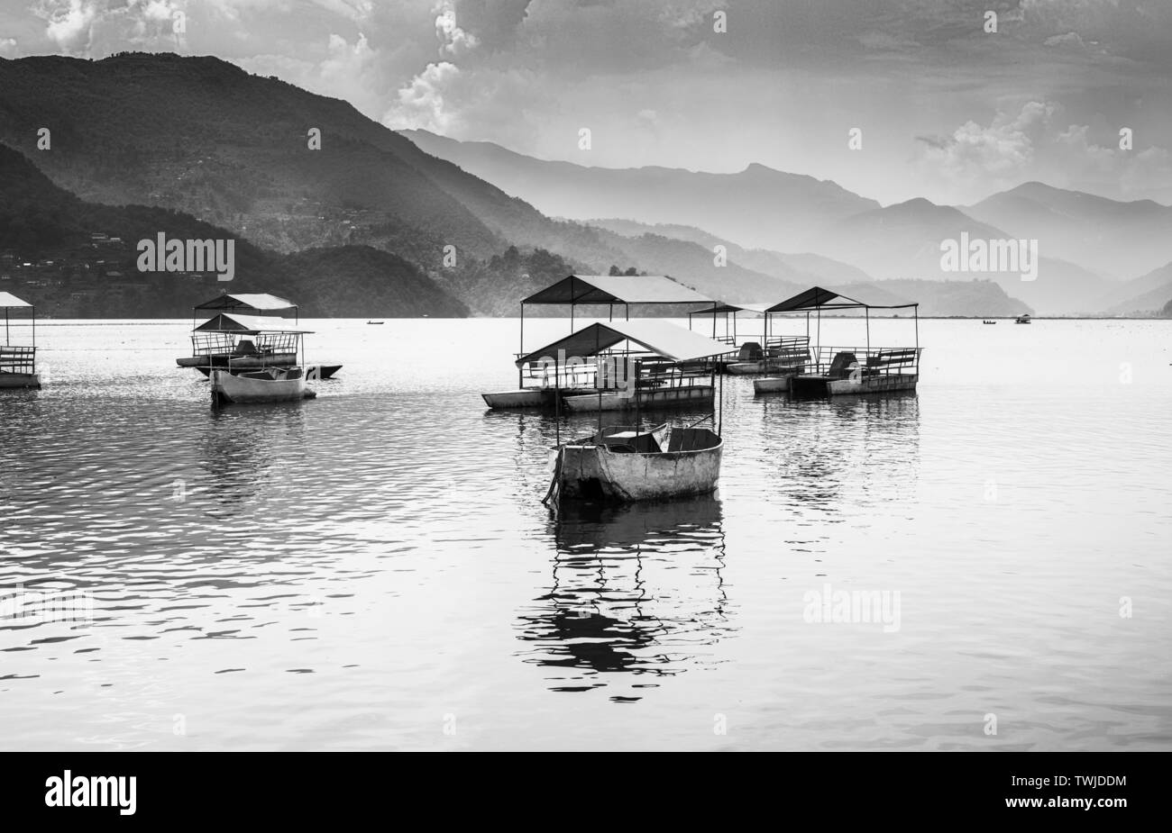 Pédalos garés dans le Lac Phewa, en noir et blanc,coucher de soleil nuages sur fond de Pokhara au Népal. Banque D'Images