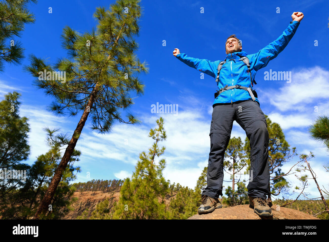 Randonnée homme atteindre haut sommet cheering célébrant en montagne avec les bras tendus vers le ciel. Happy male hiker. Banque D'Images