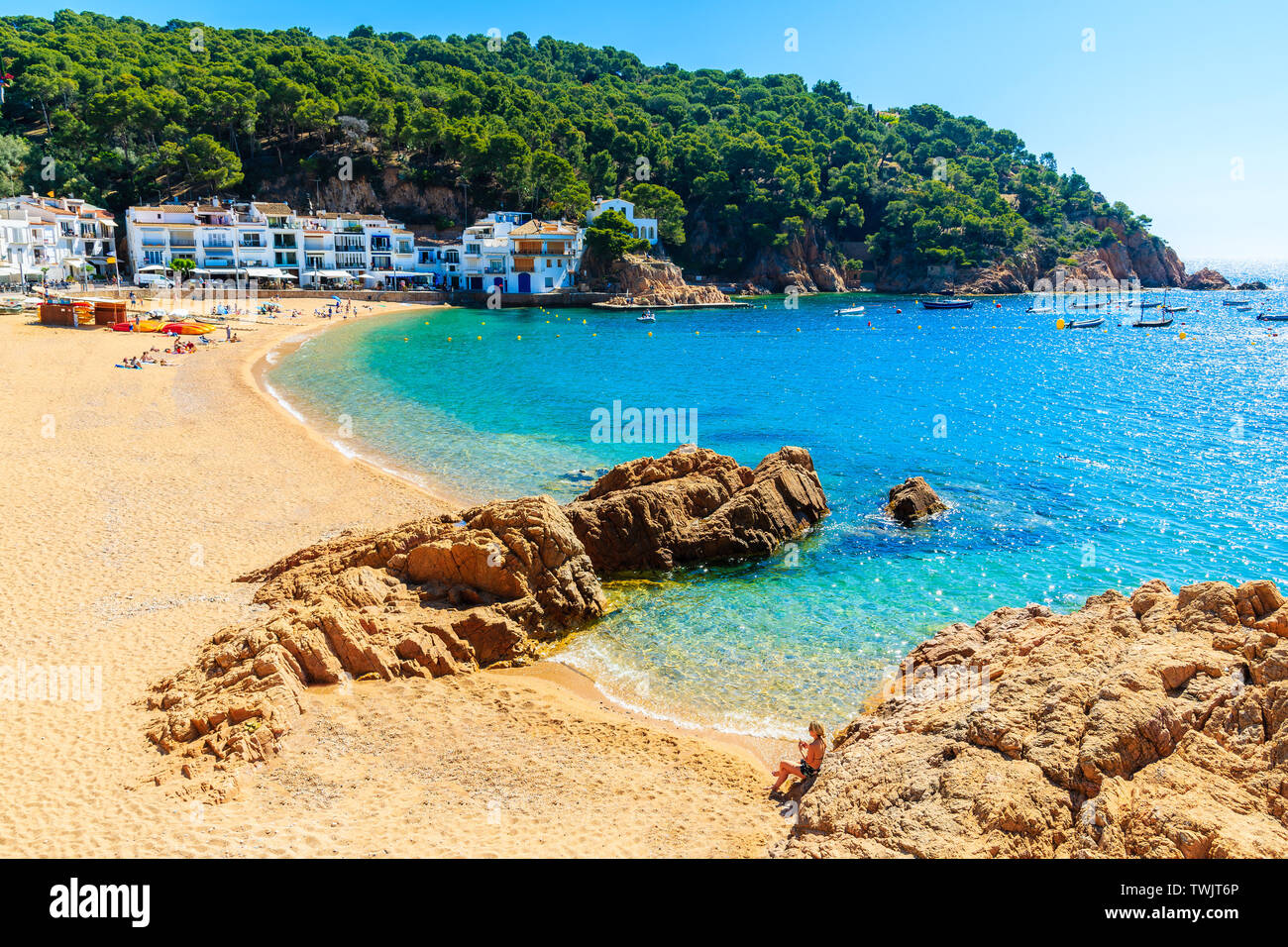 Jeune femme assise sur un rocher à très grande plage de sable à Tamariu ville en bord de mer, Costa Brava, Espagne Banque D'Images