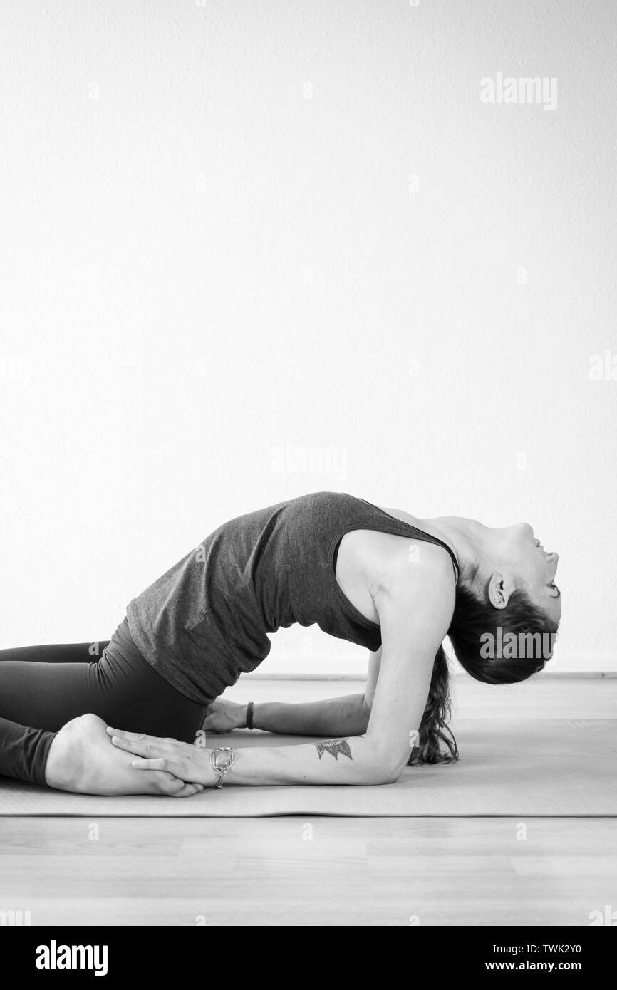 Gros plan d'une séduisante méditative européenne, femme brune de 30-35 ans pratiquant le yoga, faisant un backbend au sol Banque D'Images