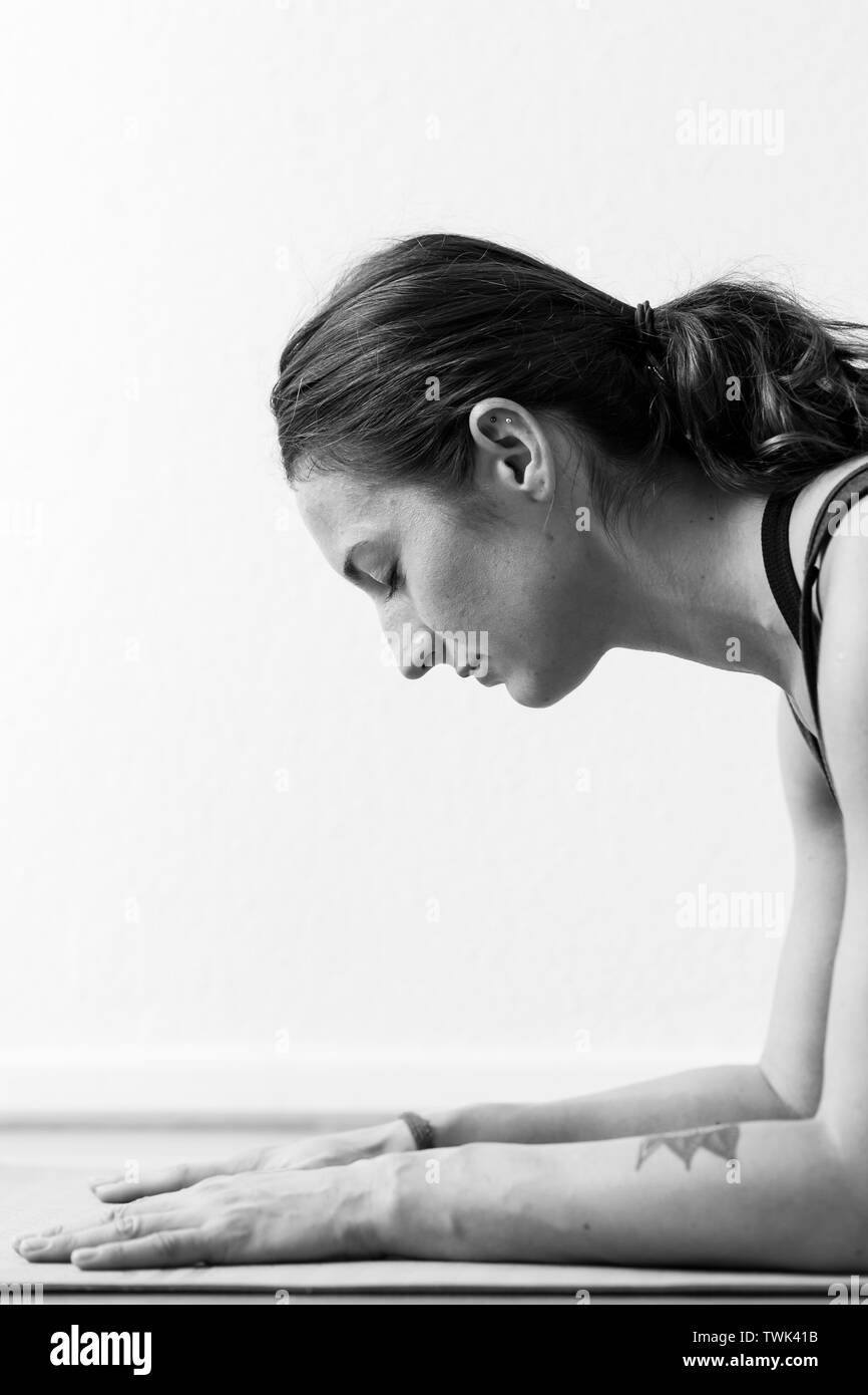 Un dark-haired femme européenne dans son 30 ans pratique le yoga à la maison. La méditation de pleine conscience, d'étirements et d'atteindre la santé physique et spirituelle. Banque D'Images