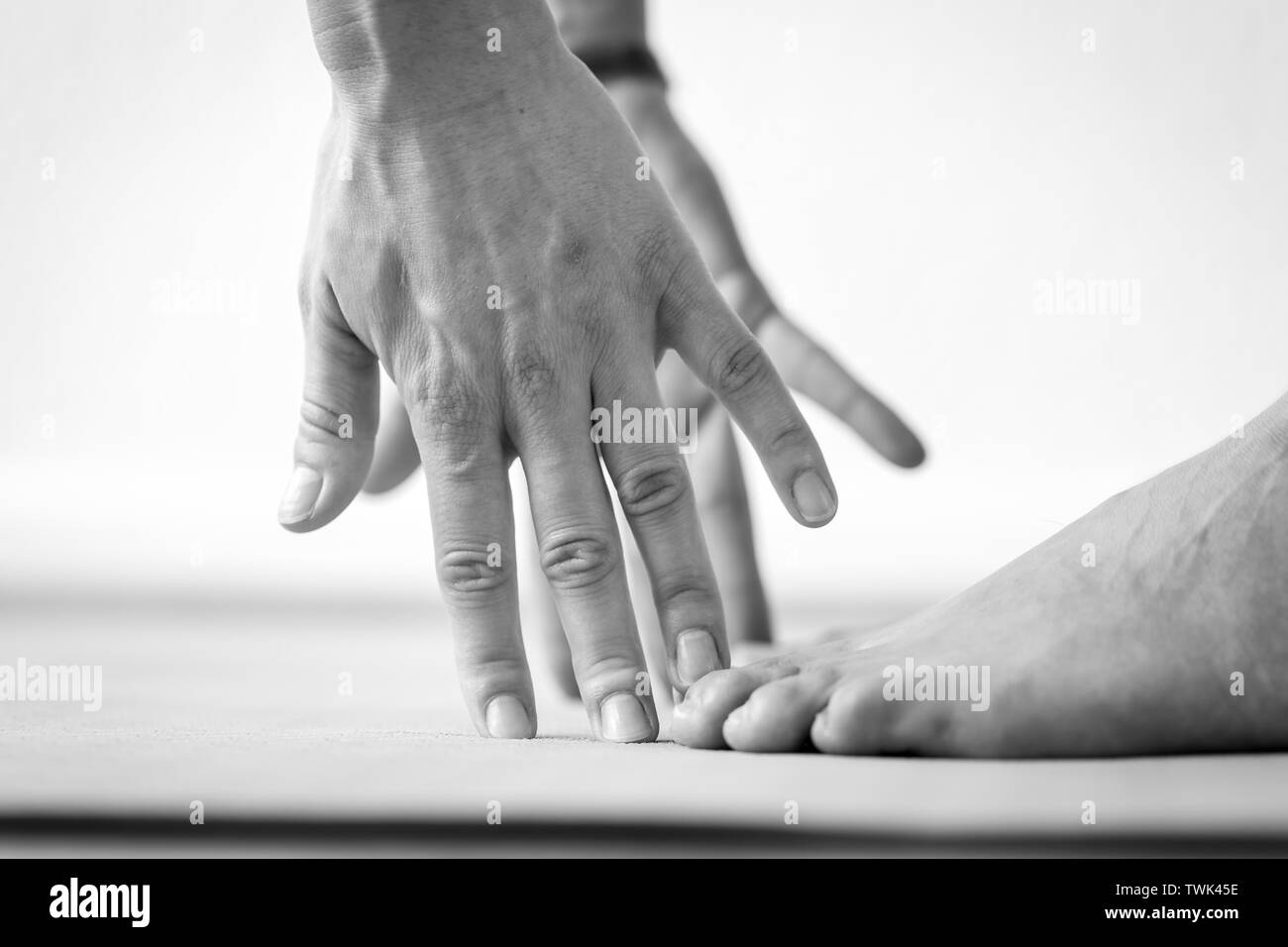 Close-up Vue de côté les mains et les pieds d'une jeune femme pratiquant Uttanasana flexion avant ou debout yoga pose, vue horizontale with copy space Banque D'Images
