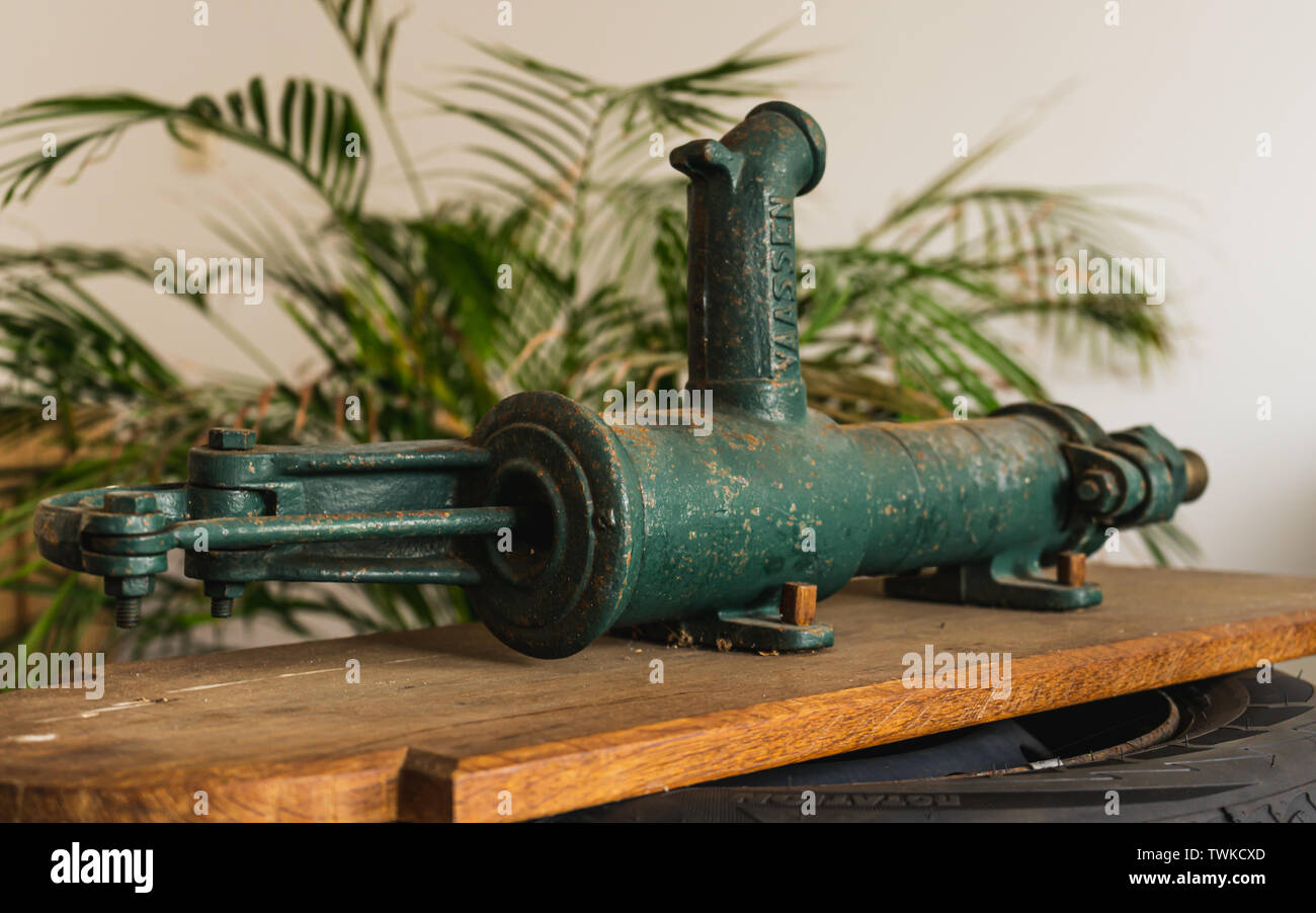 Ancien, vintage, style rétro, la pompe à eau manuelle Vassen sur planche de bois et l'arrière-plan de l'usine Banque D'Images