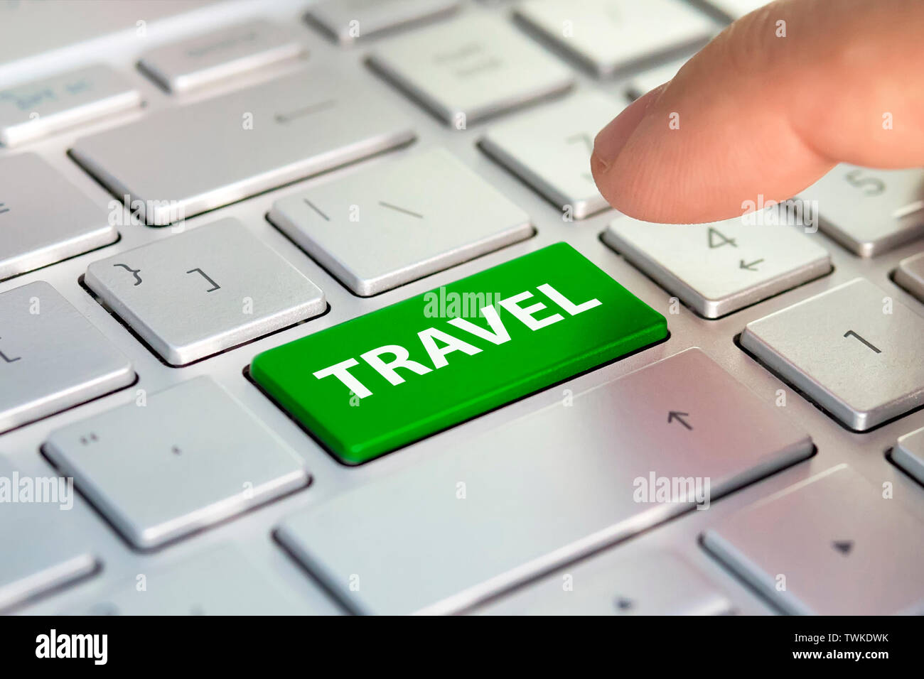 Clavier de l'ordinateur avec le bouton vert et le mot Voyage. L'office de tourisme. Doigt appuie sur le bouton de couleur grise sur le clavier. Acheter acheter des billets en ligne Banque D'Images