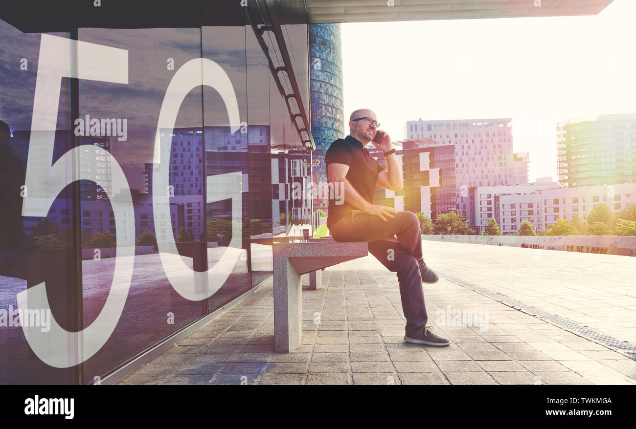 Jeune homme d'affaires à l'aide d'un smartphone avec le nouveau réseau mobile 5G. Scène urbaine dans la rue et copie vide de l'espace pour l'éditeur de texte. Banque D'Images