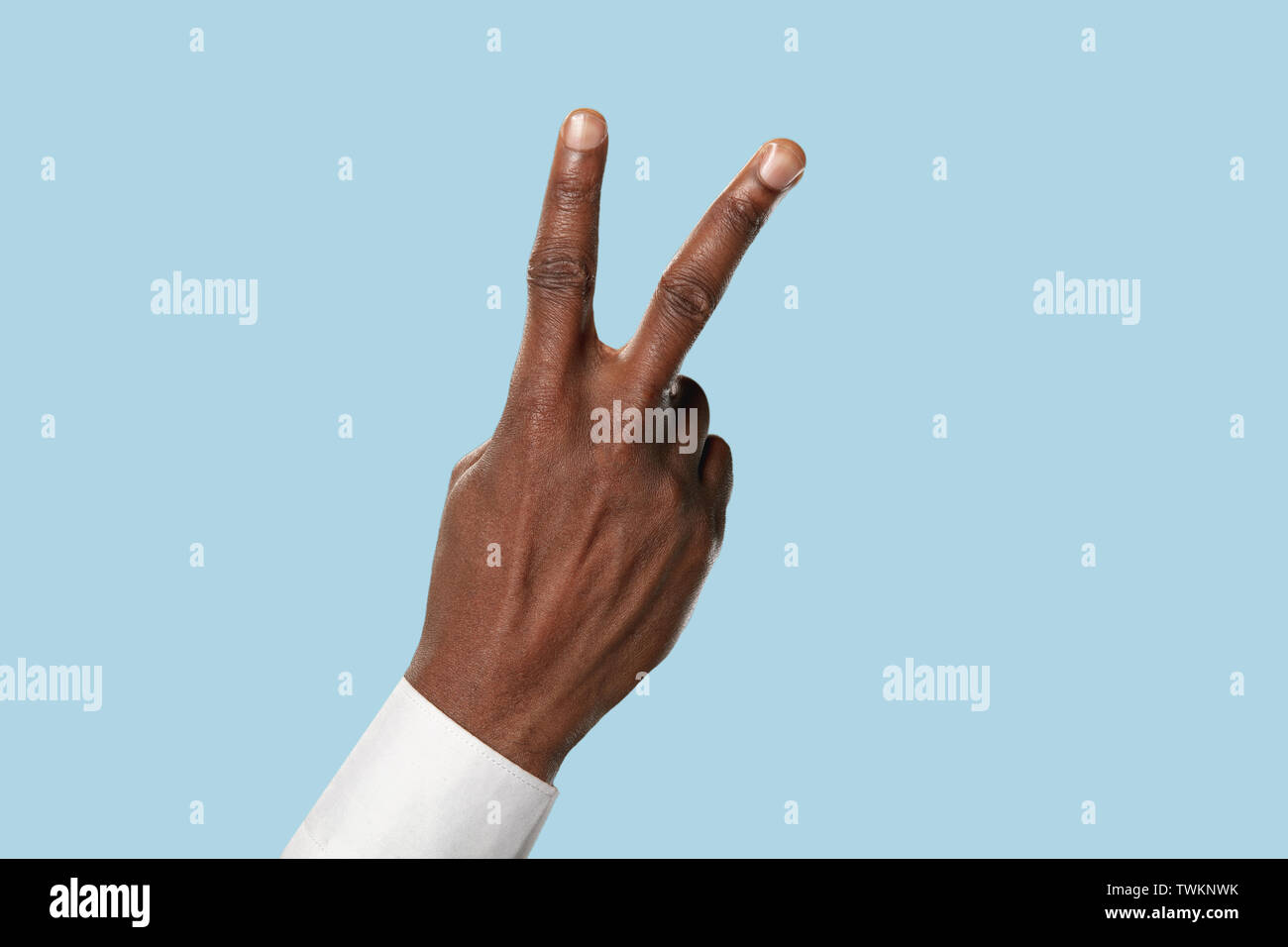 La main des hommes en chemise blanche démontrant un geste de paix et d'amitié isolé sur fond studio bleu. Concept d'affaires, bureau, travail. L'espace négatif pour insérer votre texte ou image. Banque D'Images
