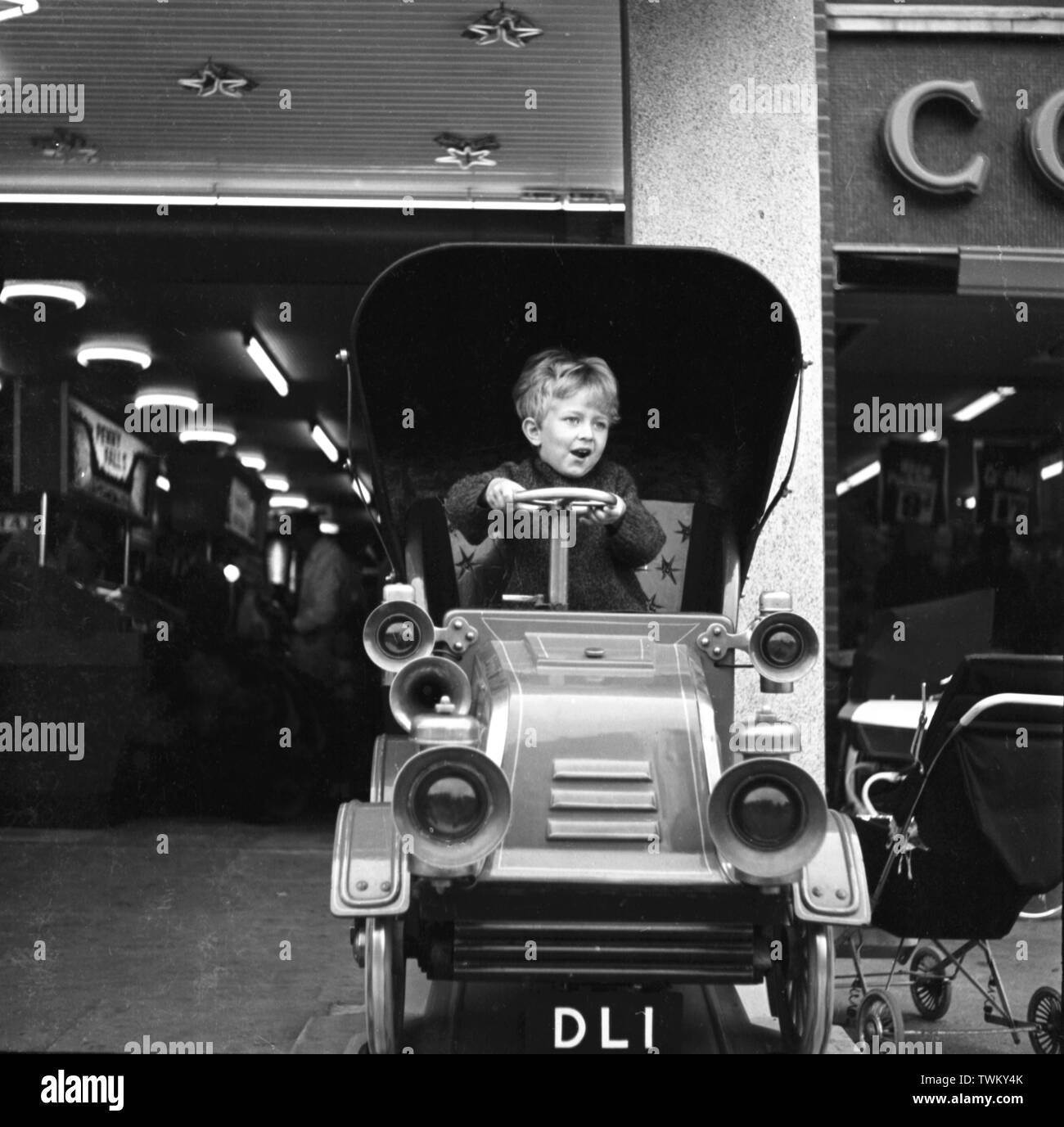 Petit garçon sur une voiture d'époque en pièces à l'extérieur d'une boutique à Keswick, Lake District. c1965 Photo de Tony Henshaw Photo par Tony Henshaw Banque D'Images