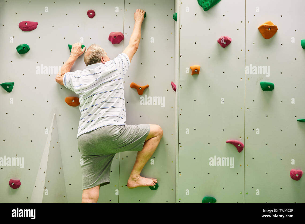 Senior man climbing dans une salle d'escalade comme un entraînement de fitness Banque D'Images