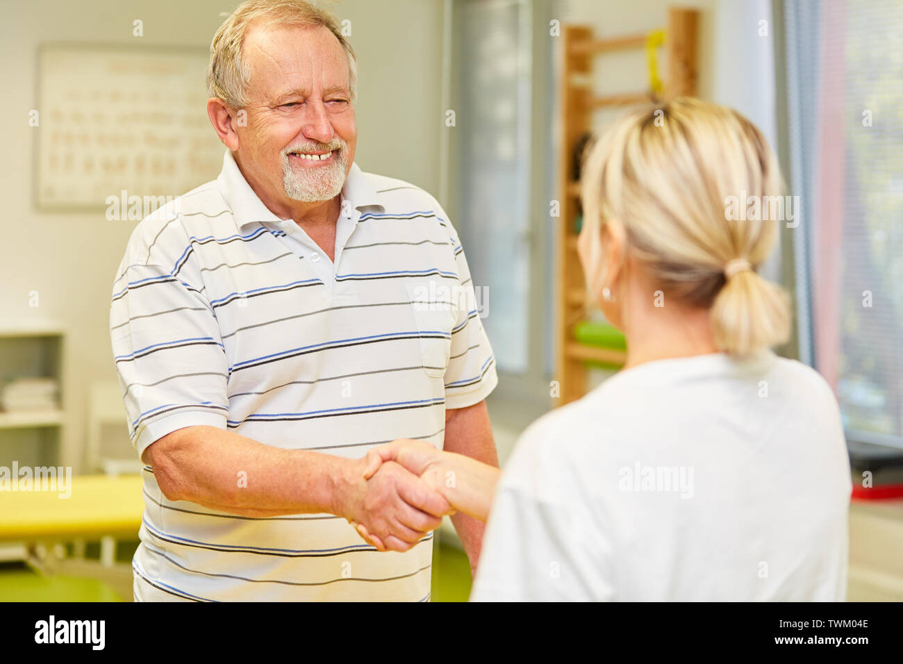 En tant que Senior patient reconnaissant, serre la main du médecin ou thérapeute pendant les heures de bureau Banque D'Images
