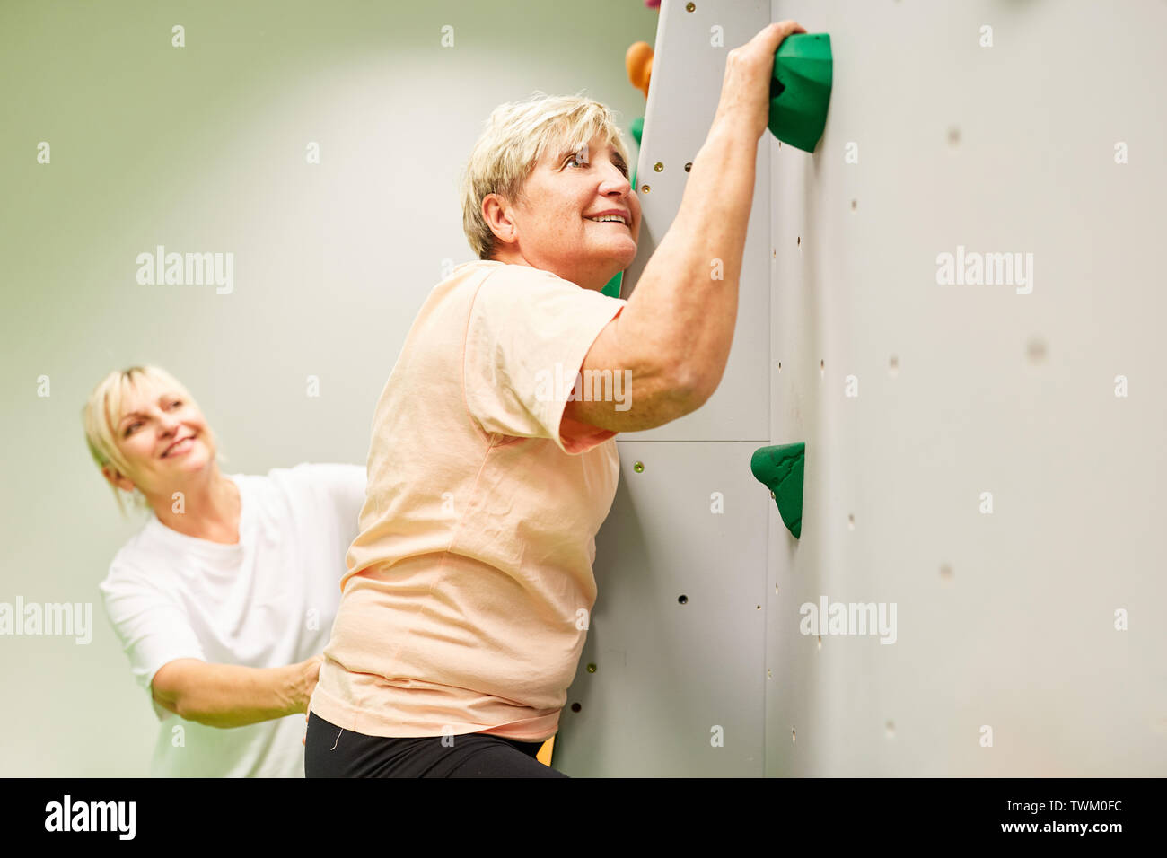 Physiothérapeute senior woman donne l'aide à grimper sur un mur d'escalade Banque D'Images