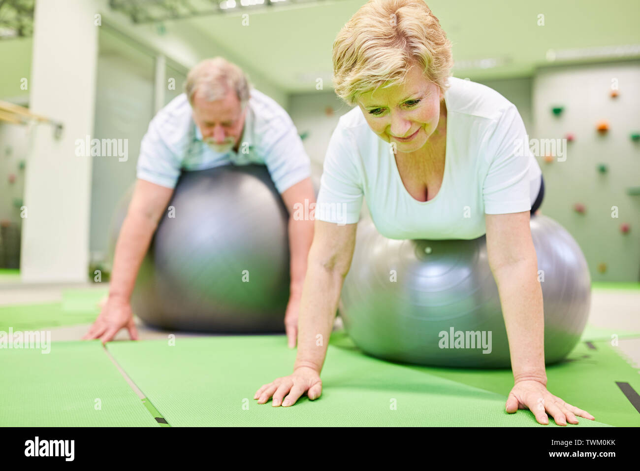 Deux personnes âgées en retour la formation avec le ballon de gymnastique en physiothérapie Banque D'Images
