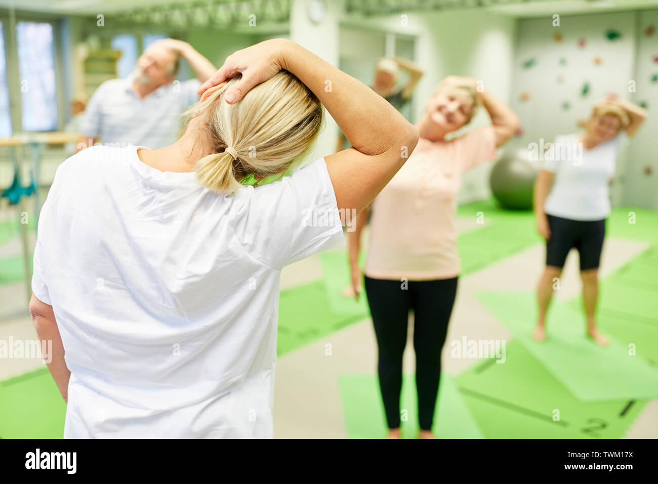 Physiothérapeute montre les aînés dans un cours d'exercices un exercice pour le rachis cervical Banque D'Images