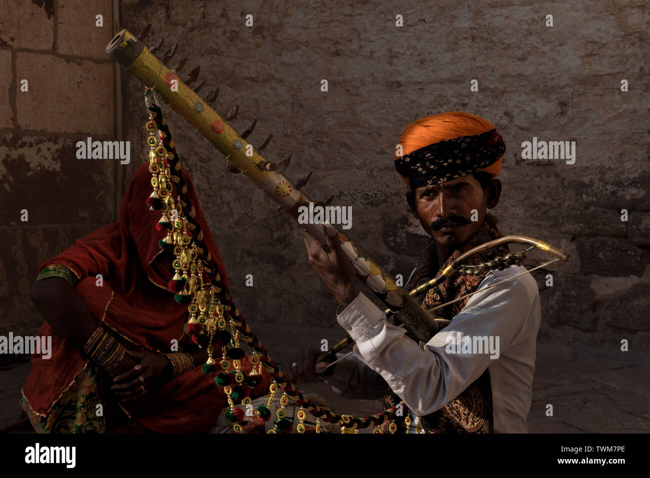 Un violoniste jouant la musique folklorique du Rajasthan à l'extérieur de Fort Mehrangarh, Jodhpur, Inde tandis que sa femme était assis sous un voile. Banque D'Images