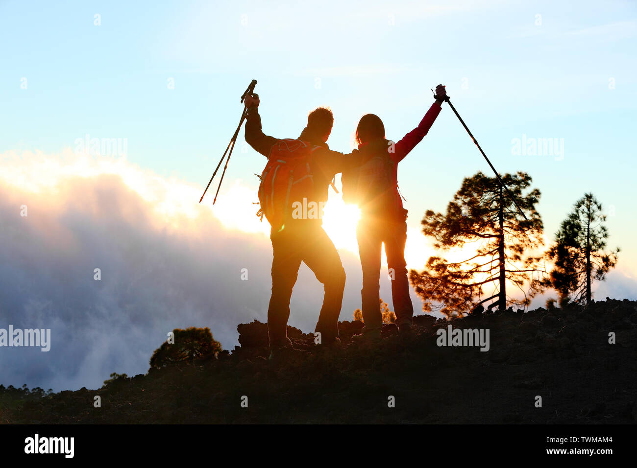 La réussite, réalisation et d'accomplissement concept avec les concepteurs de randonnée et la célébration de joie avec bras levés tendus sur le trekking randonnée pédestre à l'extérieur. Les randonneurs s'amusant au coucher du soleil. Banque D'Images
