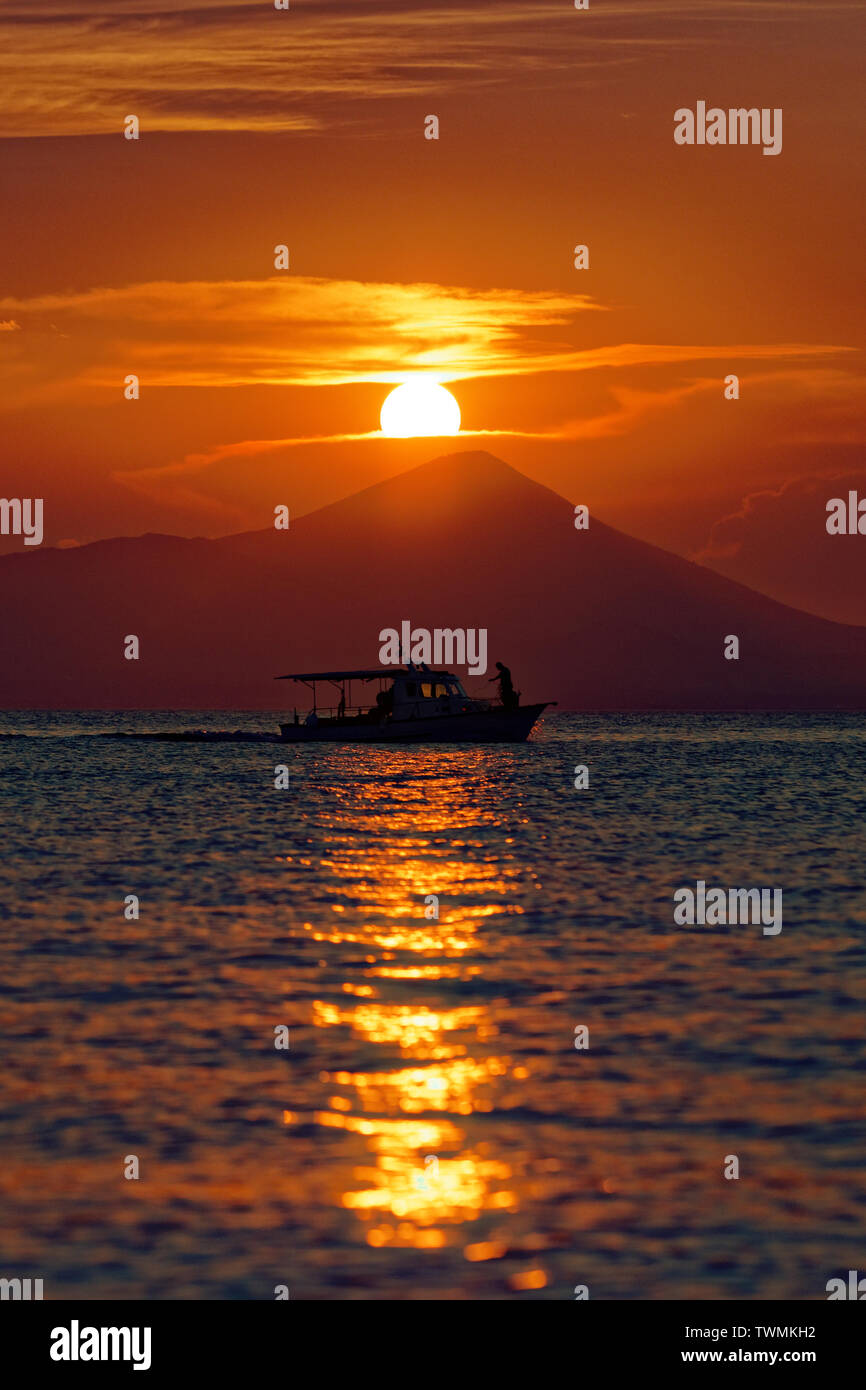 Voiles d'un bateau de pêche comme le soleil se couche sur le port, en bord de ville d'Oropos Banque D'Images