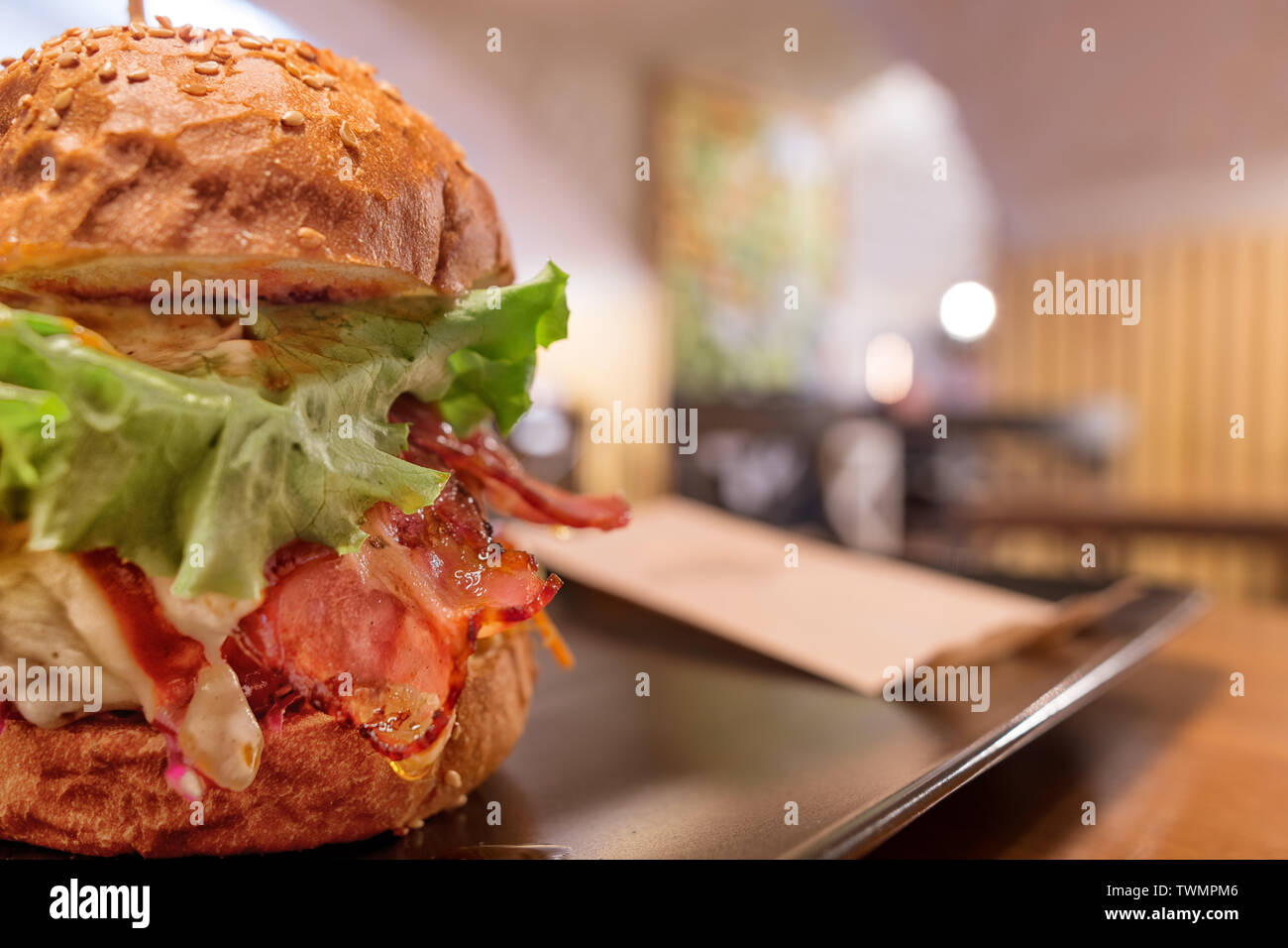 Big tasty burger avec du jambon et de la salade contre l'arrière-plan flou artistique cafe. Selective focus sur le burger Banque D'Images