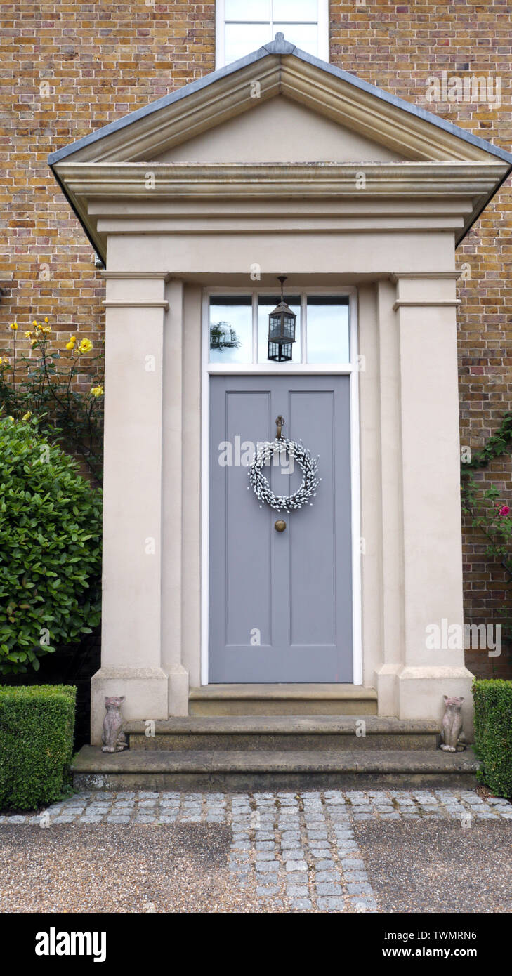 Un élégant parquet portes gris avec de la Couronne dans une vieille maison en brique, entouré de plantes vertes, Kent, Royaume-Uni . Banque D'Images