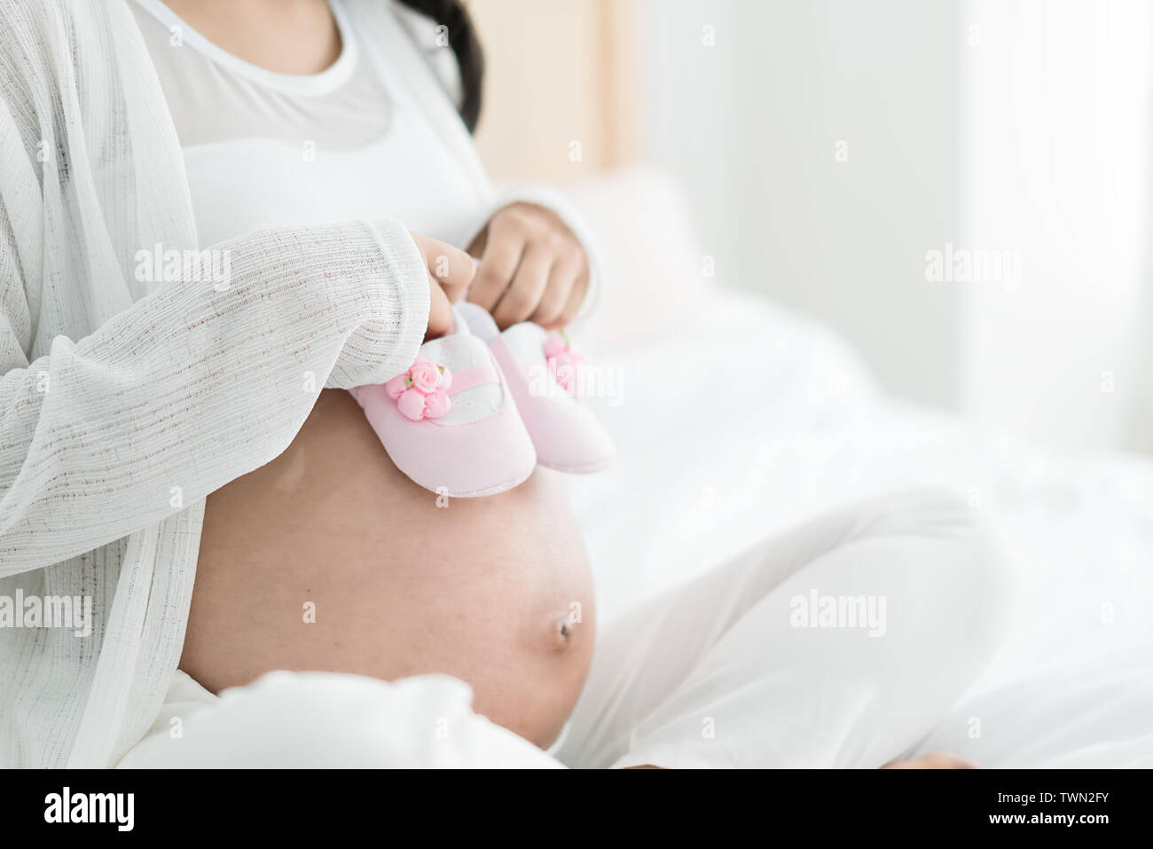 Femme enceinte avec bébé sur le lit chez lui. Profitant de la période spéciale. Banque D'Images