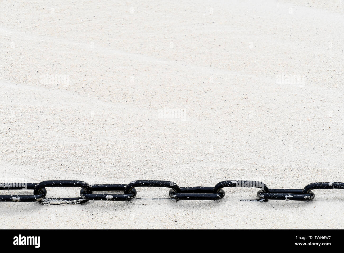 Close up of black métal chaîne dans le sable de la plage Banque D'Images