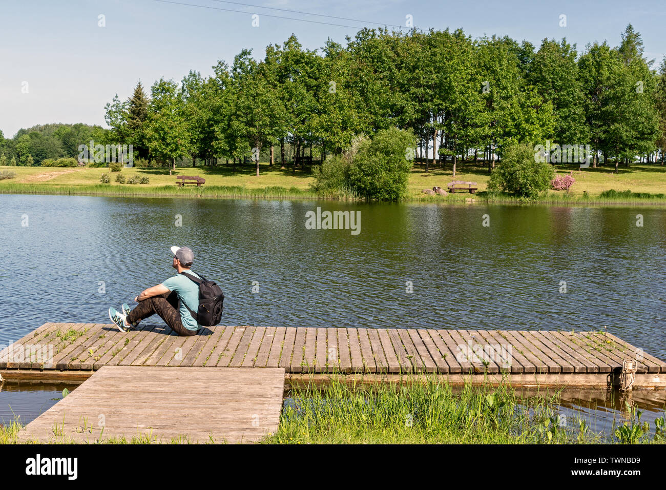 Dos de jeune homme assis sur un quai avec beau paysage Banque D'Images