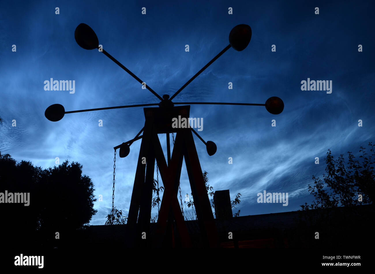 Nuit bleu acier avec noctiliucent les nuages, et la silhouette d'un moulin au premier plan. savonius Banque D'Images