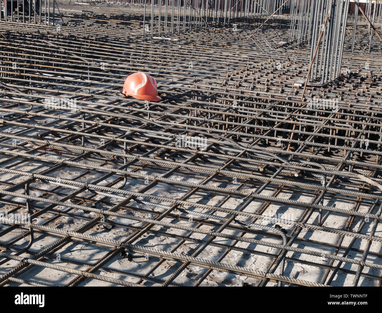 Casque orange sur la grille en acier de renfort de pied de construction résidentielle. Banque D'Images