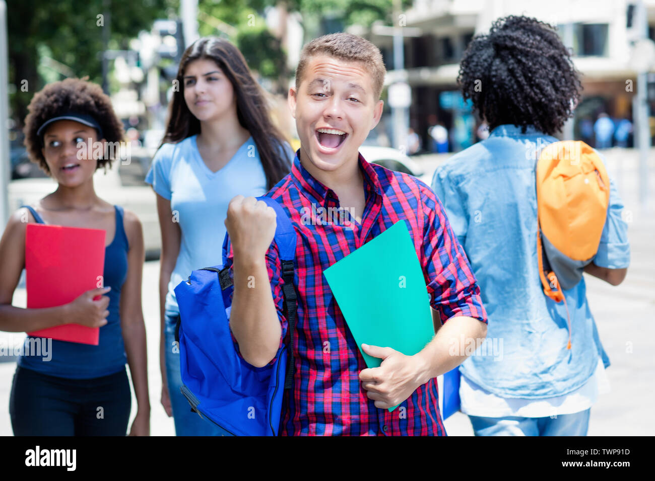 Cheering male student brésilien avec un groupe d'étudiants à l'extérieur en ville en été Banque D'Images