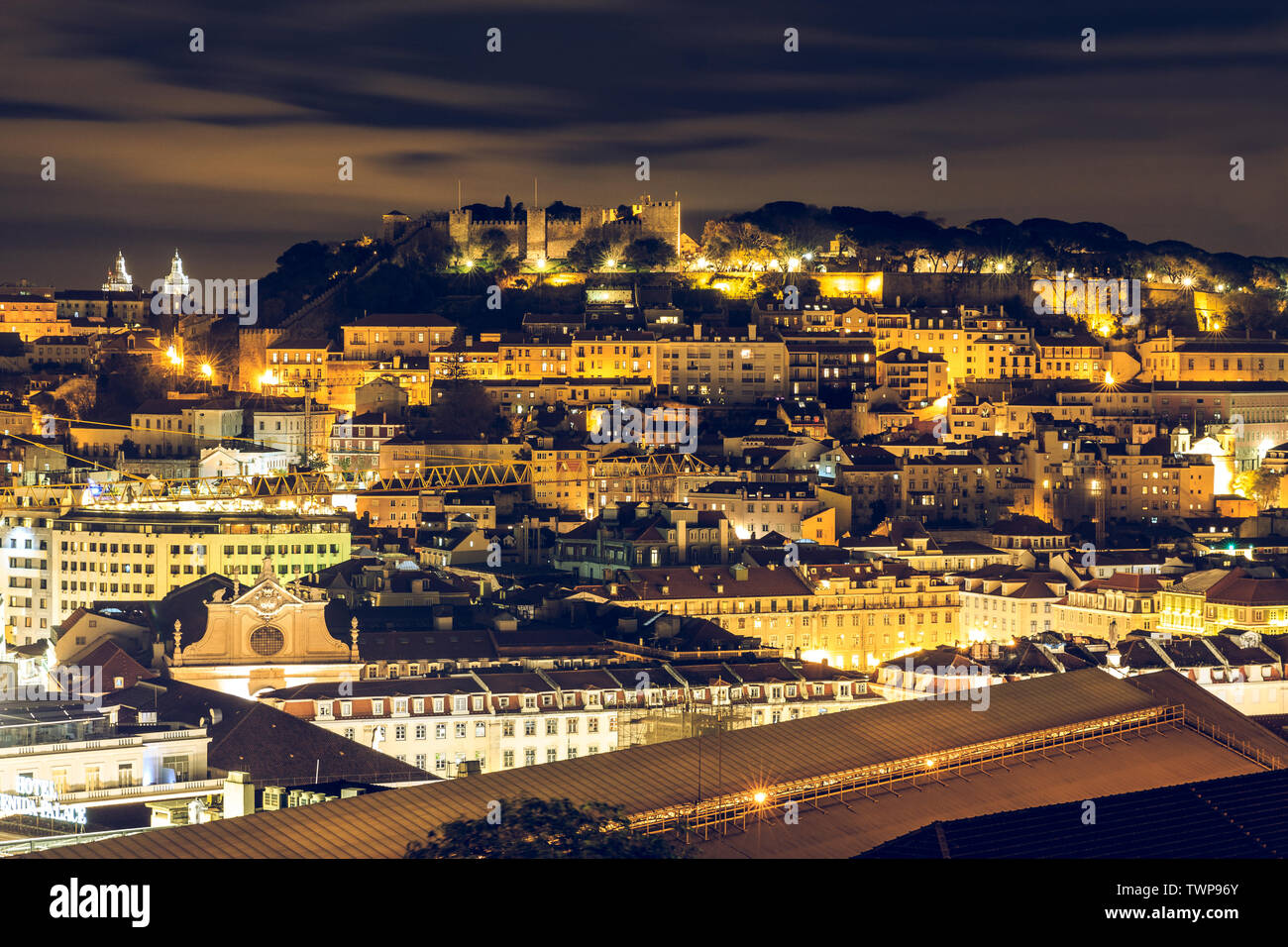 Dans la nuit de Lisbonne. La capitale du Portugal avec le château Sao Jorge de la Lookout Point. Skyline at night illuminé avec des bâtiments et des toitures. Banque D'Images