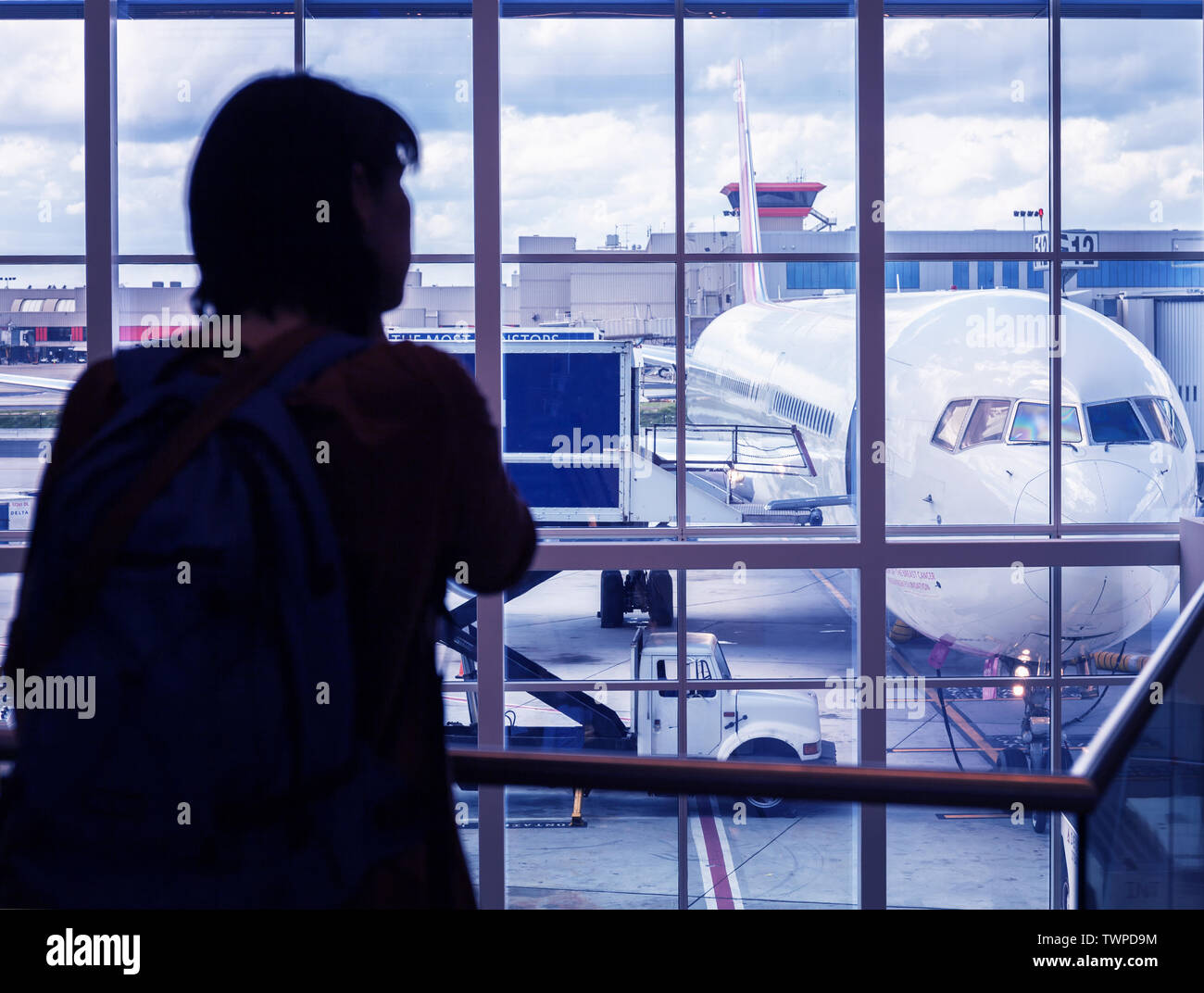 Silhouette d'une jeune femme est debout à l'aéroport par la fenêtre à la recherche lors de la préparation du vol de l'aéronef. Banque D'Images