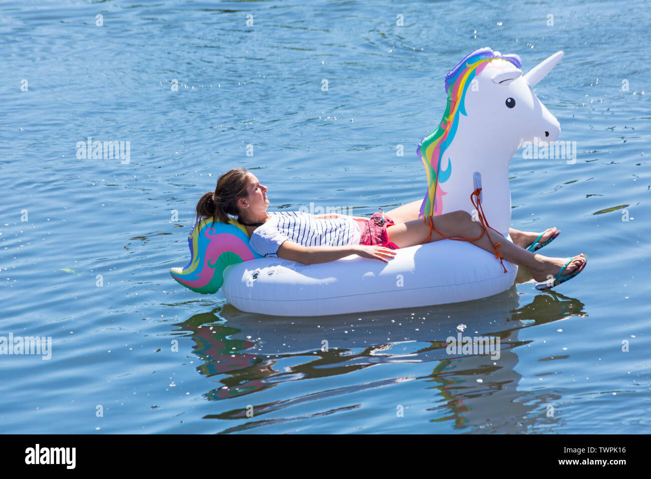 Iford, Dorset, UK. 22 juin 2019. Un temps magnifique, ensoleillé et chaud, toujours pour Dorset Canot Journée avec des centaines de jeux gonflables, des dériveurs, artisanat, conseils formant une flottille, de mettre les voiles de l'IFORD pont rivière Stour de Tuckton bridge. L'événement a commencé en 2014 comme un petit peu de plaisir, mais est maintenant devenu un événement annuel recueillant des fonds pour des organismes de bienfaisance et fonceur plus grand chaque année. Young woman relaxing on unicorn gonflable gonflable. Credit : Carolyn Jenkins/Alamy Live News Banque D'Images