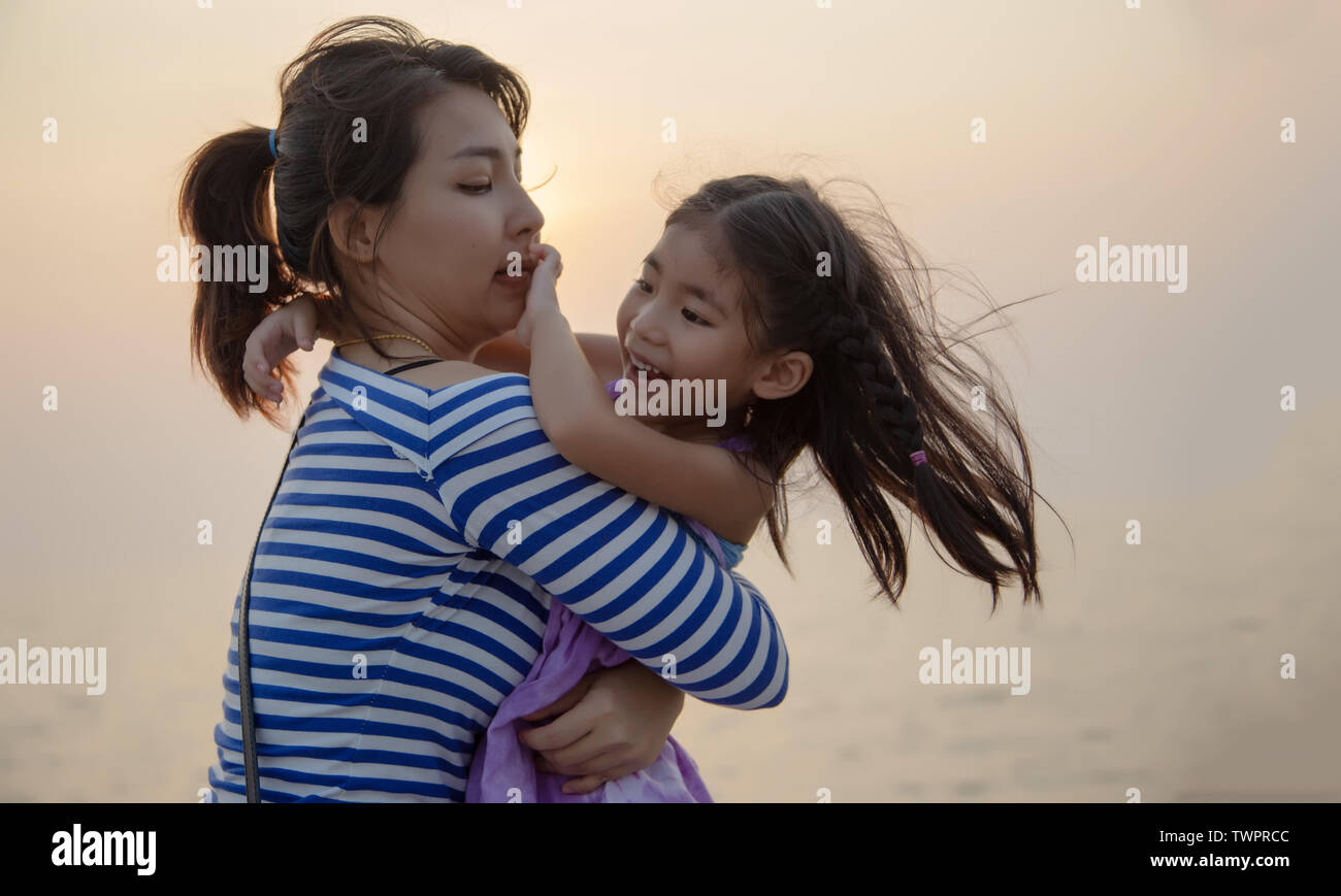 Beau moment avec maman et enfant jouer et câlin avec coucher du soleil lumière chaude. L'amour en famille Banque D'Images