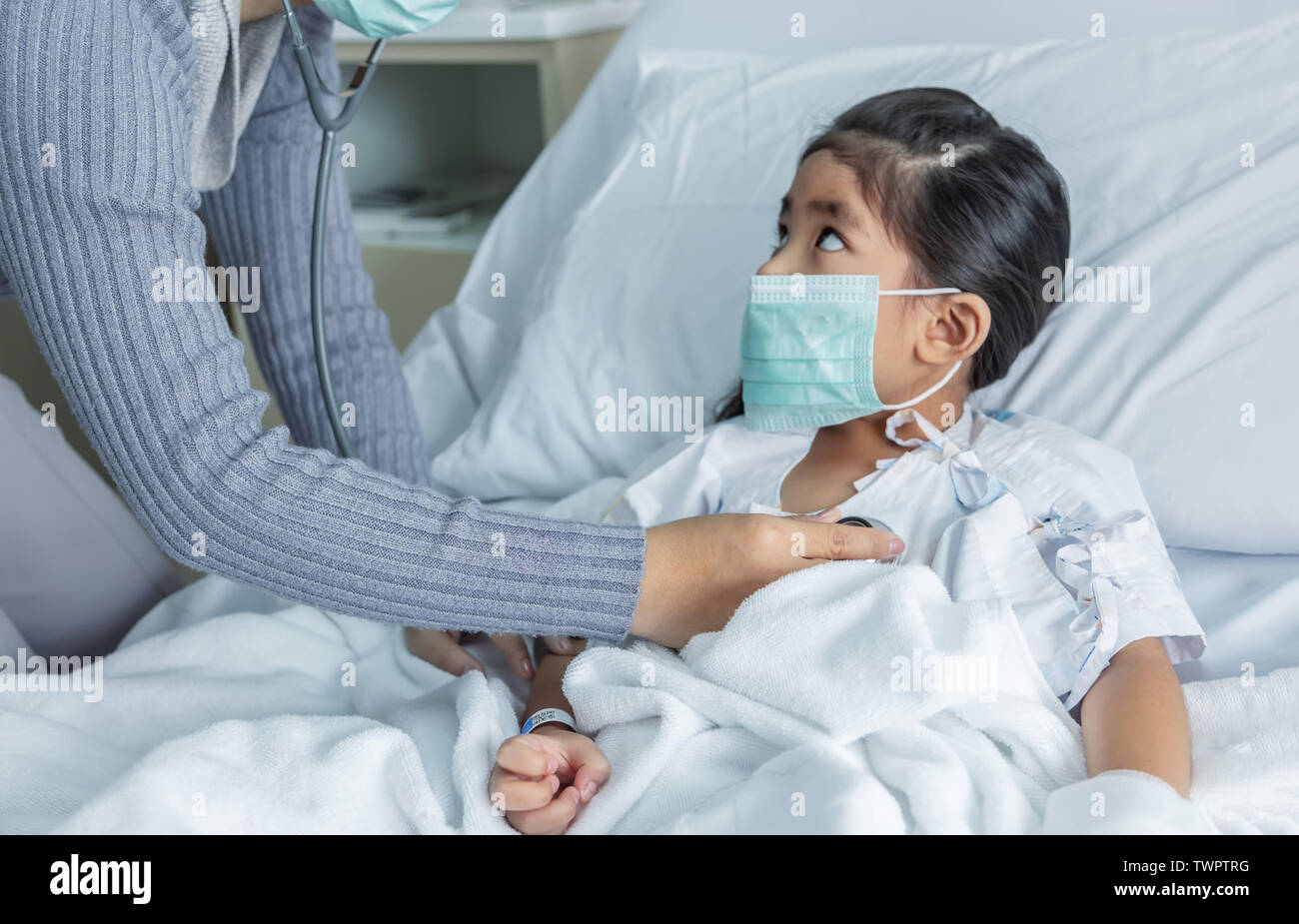 Médecin guérir Grippe A ou H1N1 asian kid sur lit d'hôpital. Virus médecine situation lorsque kid ont une forte fièvre. Utilisation médecin stéthoscope pour entendre Banque D'Images