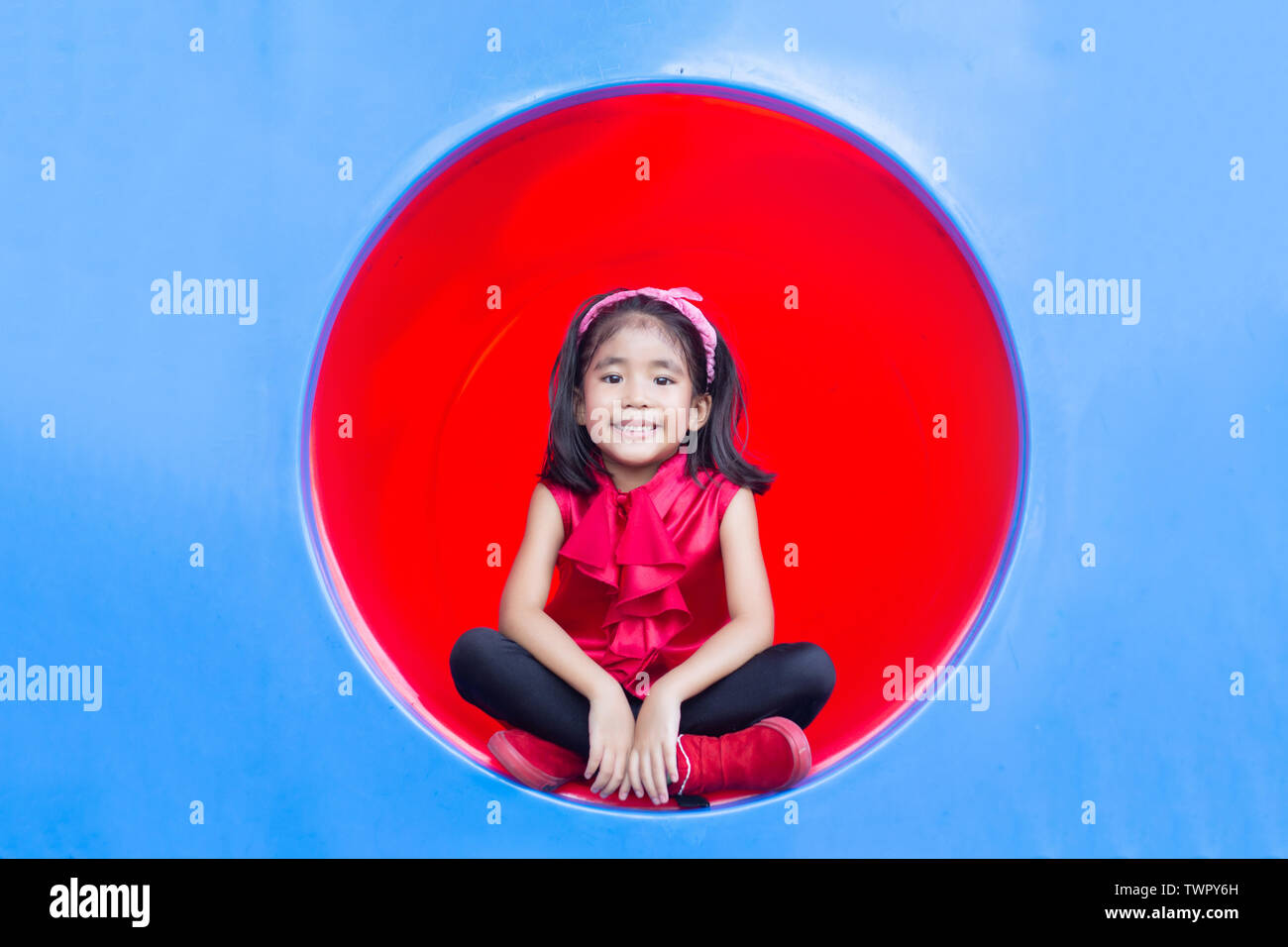 Sourire heureux enfants asiatiques sur cercle de jeux tennel en plastique Banque D'Images