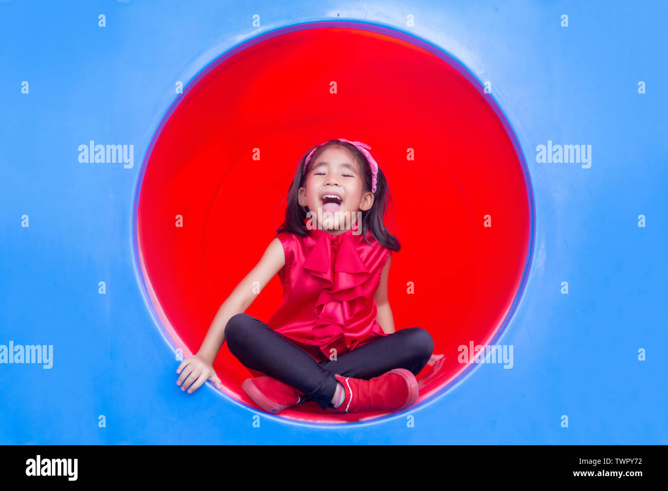 Sourire heureux enfants asiatiques sur cercle de jeux tennel en plastique Banque D'Images
