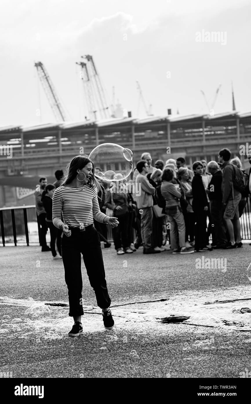 Une femme blanche à jouer avec une grosse bulle sur une belle journée à Londres Banque D'Images