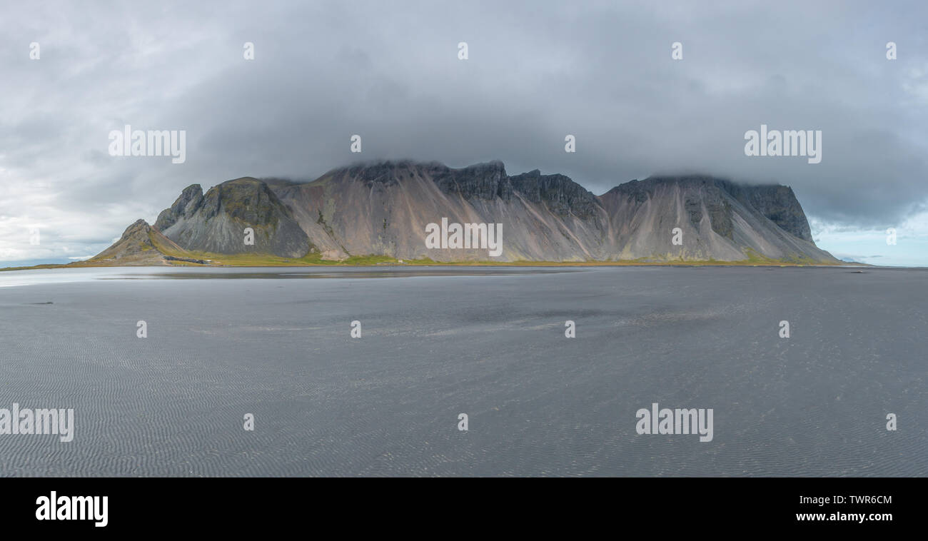 Vue panoramique des montagnes Vestrahorn en Islande pendant la marée basse. Plage de sable noir en face d'une chaîne de montagnes côtières. Banque D'Images