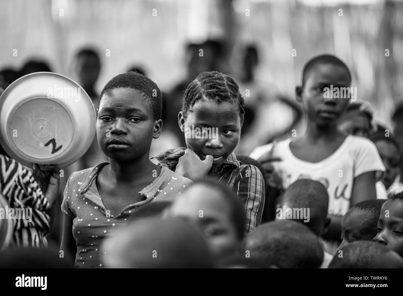 Photo en noir et blanc de jeunes Africaines attendent en ligne pour obtenir de la nourriture pour manger Banque D'Images