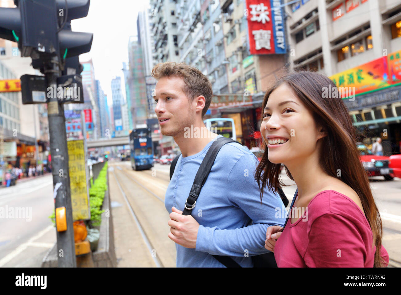 Hong Kong, les gens marcher à Causeway Bay crossing route très fréquentée avec tramway. Course mixte urbain chinois asiatique / Caucasian woman smiling happy vivant en ville. Banque D'Images