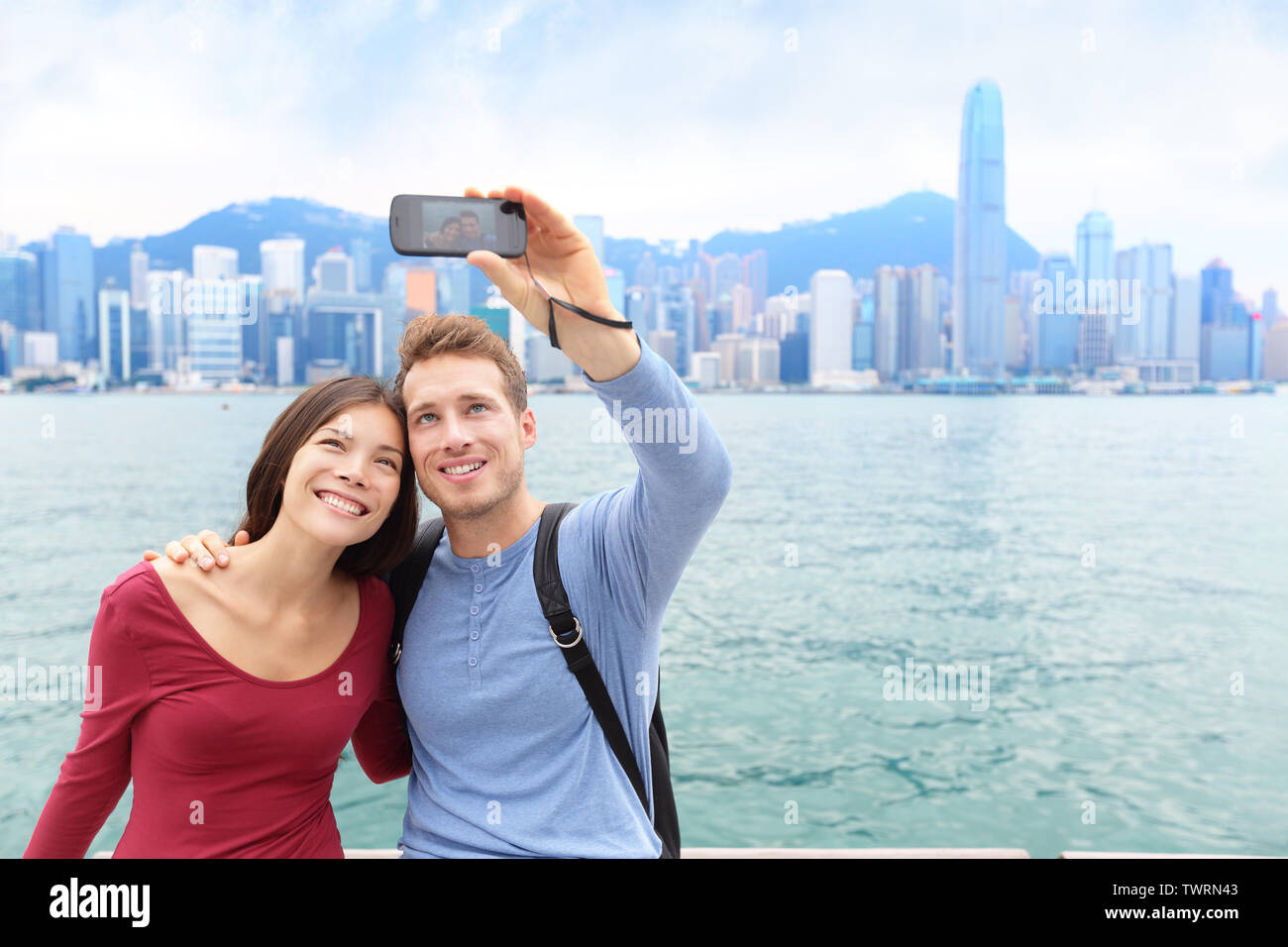 Les touristes selfies couple taking self-portrait photo in Hong Kong bénéficiant du tourisme à Tsim Sha Tsui, Promenade et l'Avenue des Stars à Victoria Harbour, Kowloon, Hong Kong. Concept de voyage. Banque D'Images