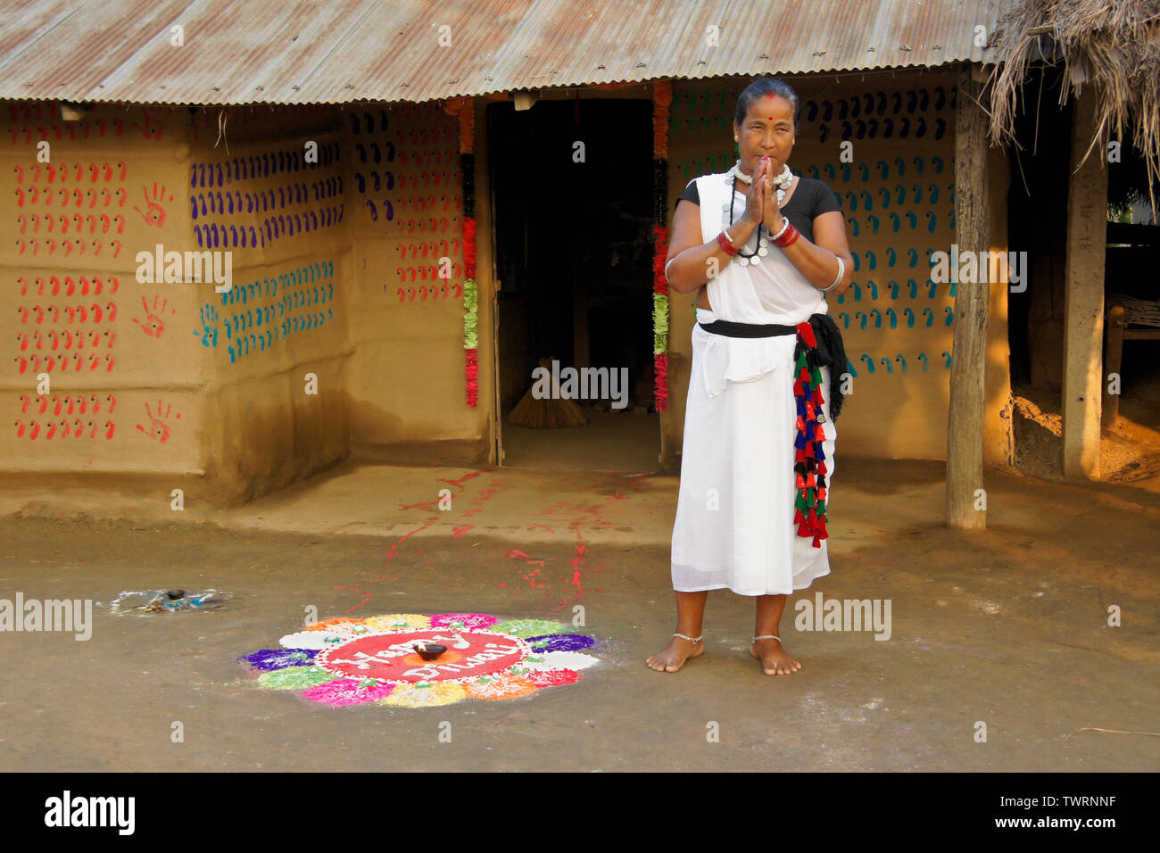 Femme de l'ethnie Tharu debout devant sa maison qui est décoré pour Diwali, maison de vacances près de Chitwan, Népal Banque D'Images