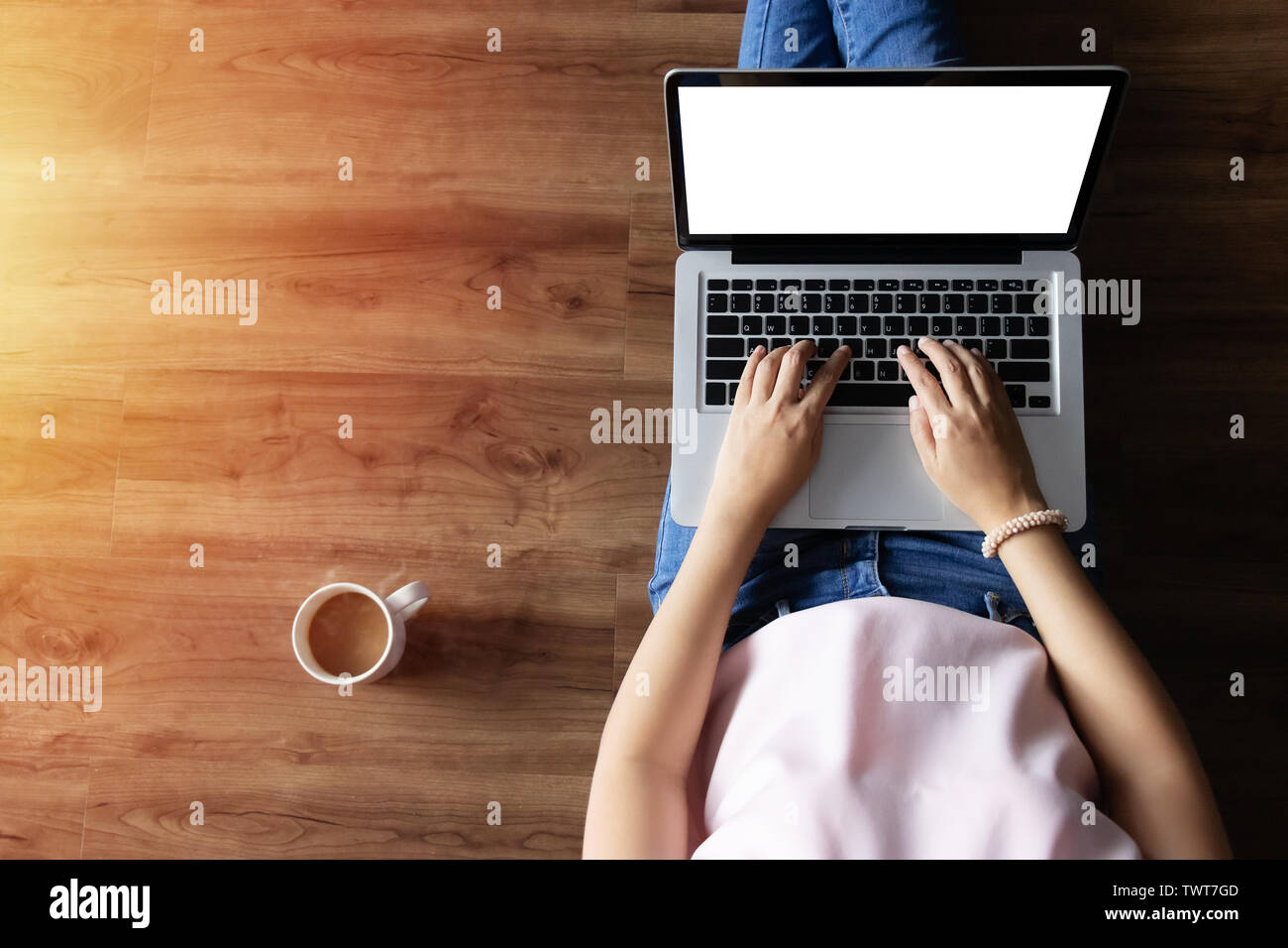 Top View of woman typing on laptop Ordinateur avec écran blanc de la maison sur un plancher en bois avec copie espace Banque D'Images