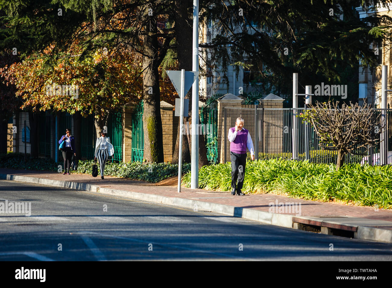 Un homme d'affaires marchant et parlant au téléphone dans le quartier des affaires de Sandton, Johannesburg, Afrique du Sud. Banque D'Images